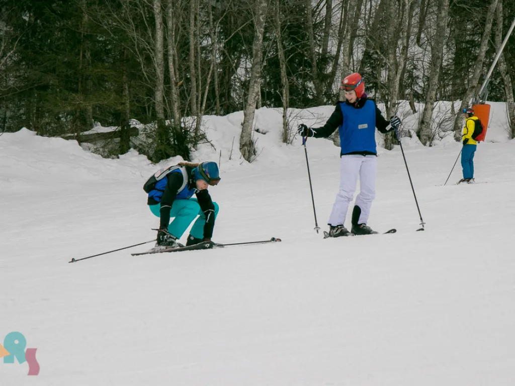Skifahrende üben am Hang, eine Person kniet im Schnee.